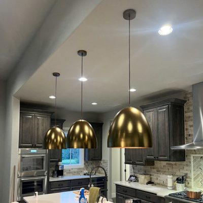 A modern kitchen featuring three elegant pendant lights hanging over the island, enhancing the kitchen's stylish and contemporary design.